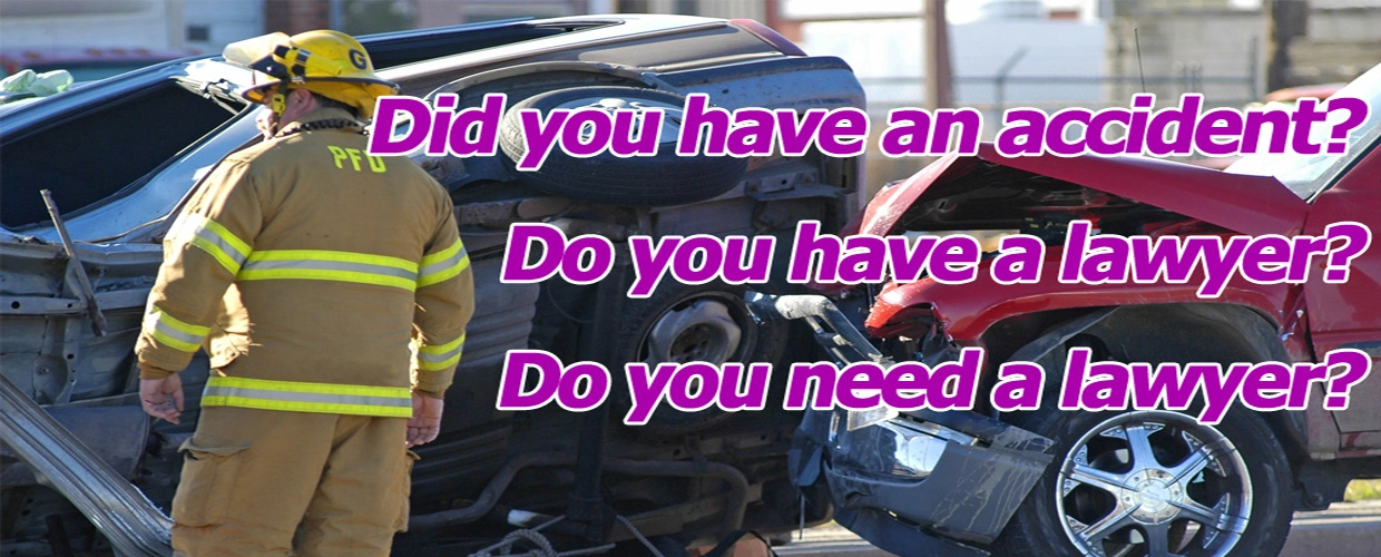 A fireman standing next to an overturned car.